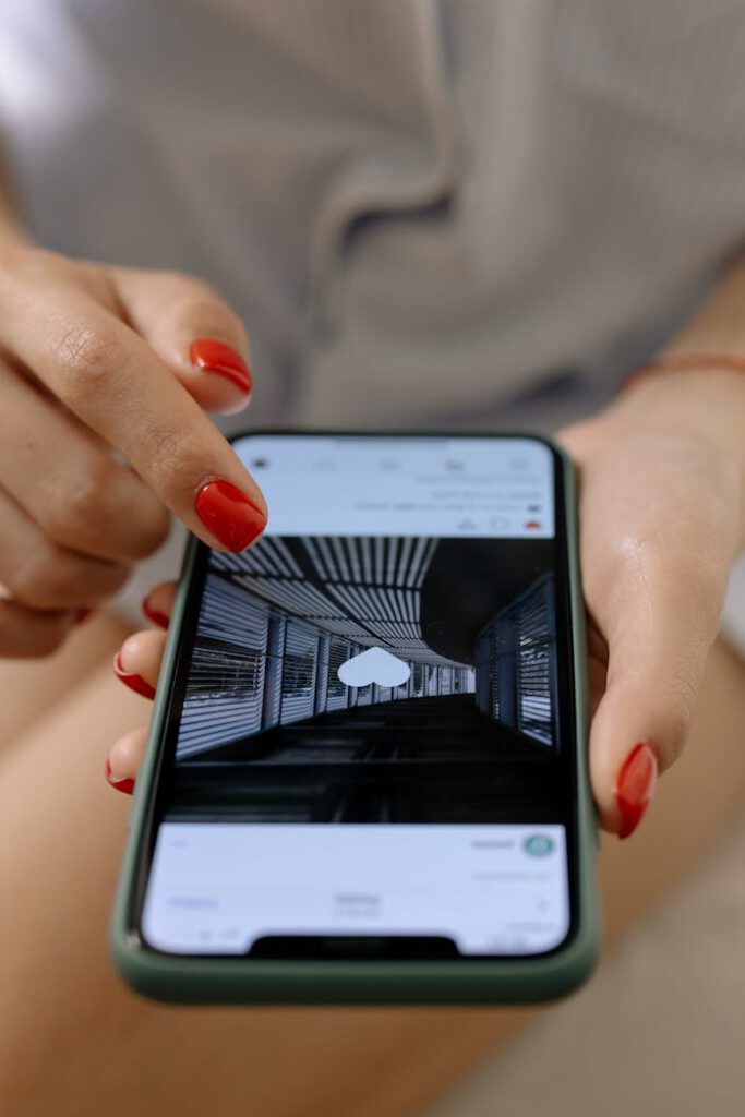 pexels-photo-6963585 A woman with red nails uses a smartphone to browse social media indoors.
